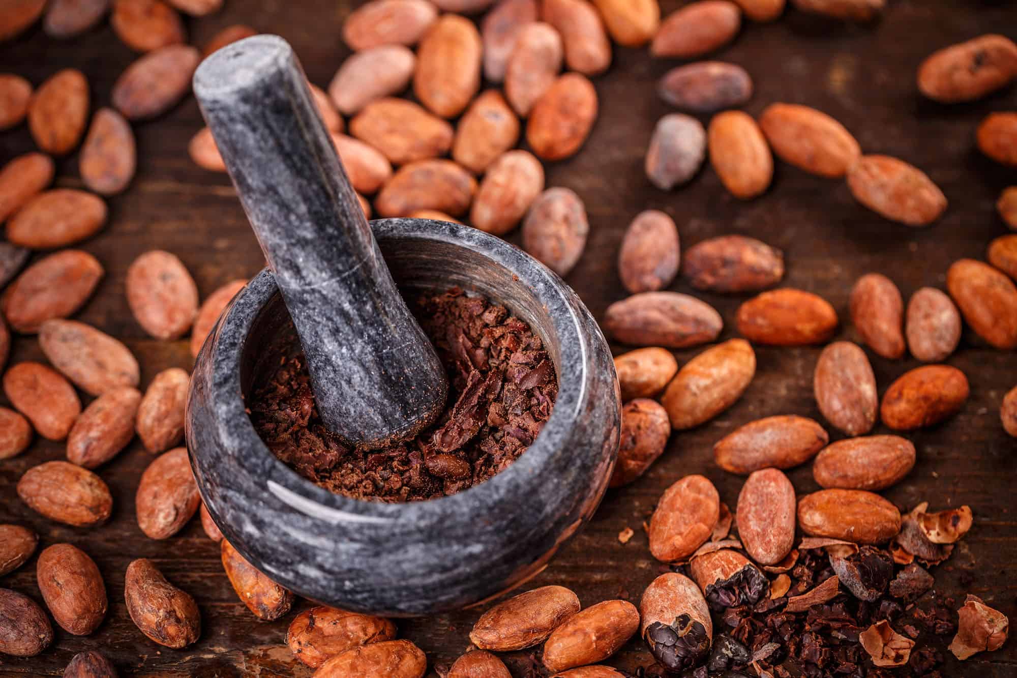 Cocoa beans being ground in mortar and pestle